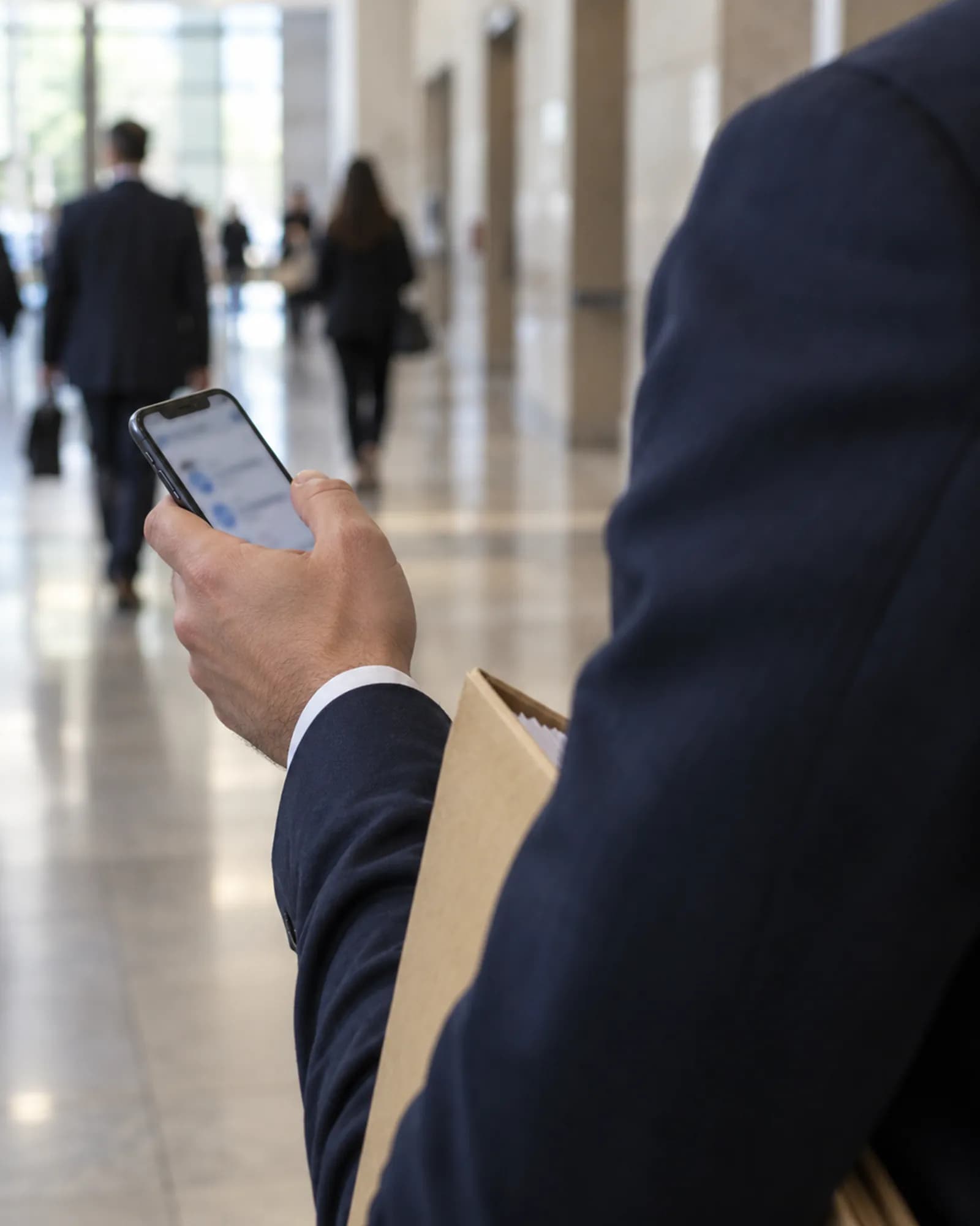 HukukBis mobil Adliye koridorunda telefonundan dava ajandasına bakan avukat